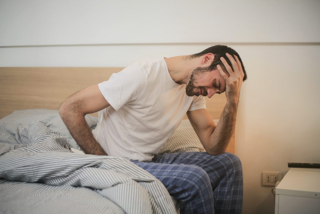 Młody człowiek w piżamie cierpiący na ból głowy rano