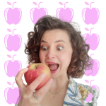 Une femme tenant une pomme devant un fond rose.